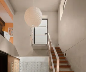 Modern staircase design with wood steps, concrete walls, and an aluminum railing.