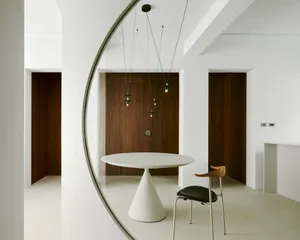 Modern white dining room with concrete floor, minimalist design, and aconic table.