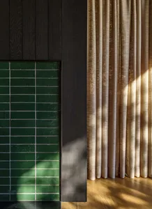 Modern interior design featuring a window treatment adorned with green tiles.