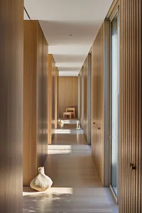 A modern wooden corridor with a small woven vase at the entrance.