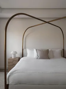A minimalist bedroom with a brass headboard and fabric cushions