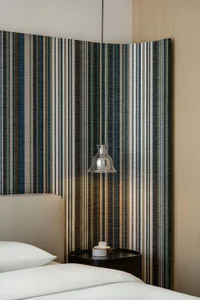 Modern minimalist bedroom featuring a striped fabric panel on the headboard, creating a stylish and sleek design.