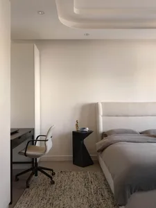 Minimalist bedroom featuring white fabric furniture and a cozy, neutral color palette.