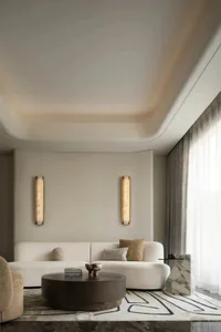 A minimalistic living room with a white sofa, marble coffee table, and textured fabric accents.