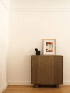 Minimalist interior design featuring a wooden cabinet with a scalloped edge.