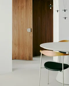 A minimalist interior design featuring a wooden dining table and chairs, with a white table and black chairs.