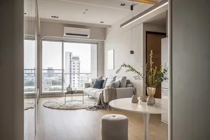 A minimalist living room with neutral tones and a city view through large windows.