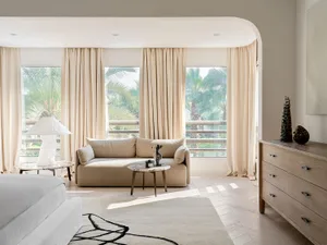 A minimalist residential interior with neutral-toned textiles, glass, and wood materials.