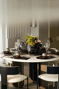 Modern dining table with marble top, surrounded by black and white chairs, featuring an artistic centerpiece with vibrant flo