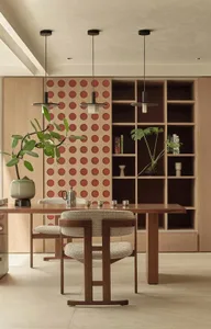 Modern dining room with wooden table, chairs, and bookshelf, featuring a wall-mounted shelf with circular cutouts.