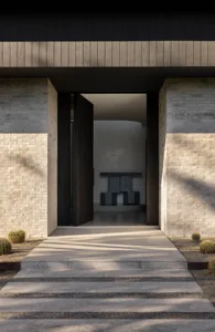 A modern entryway featuring brick and concrete materials, with an open door inviting into a light-filled interior.