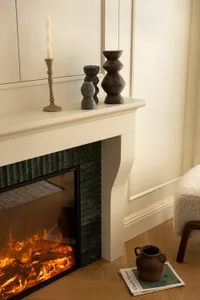 A modern fireplace with a marble mantel, featuring decorative vases and a lit fire.