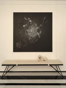 A modern house with an abstract black and white artwork on the wall and a neutral-colored bench with a small white dog sittin