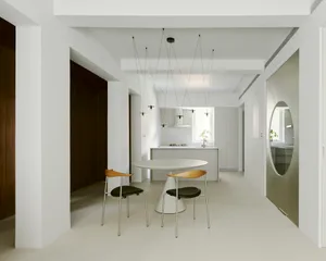 Modern kitchen with white concrete flooring, minimalist dining area, and sleek, clean lines.