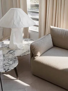 A modern living room featuring a marble coffee table, lamp, and a contemporary sofa with neutral tones.