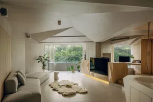 A modern living room with natural wooden furniture and light-colored flooring.