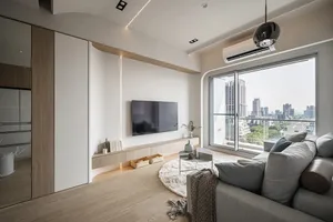 Modern living room featuring sleek white walls, wooden flooring, and a large window overlooking a city skyline.