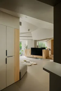 Modern living room with wood and concrete finishes, featuring a sleek entertainment unit and large windows.