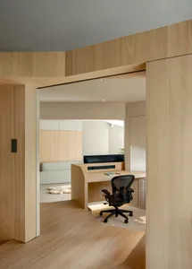 A modern minimalist office featuring a wooden desk and chair, with a sleek design and natural lighting.