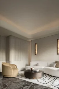 Modern living room with a curved white sofa, round coffee table, and neutral-toned wall and floor treatments.