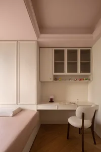 Minimalist bedroom with pink bedding and a wooden desk.