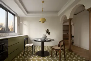 Modern residential dining room featuring a round table with a vase and a book, two chairs, and a patterned floor, set in a co