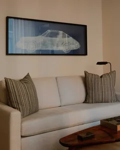A comfortable living room with a beige couch, black and brown striped throw pillows, a dark wooden table, and a framed x-ray 