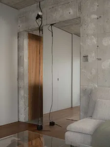 Modern minimalist living room with concrete walls and wooden floor.