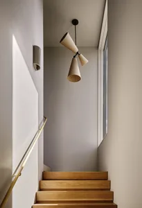 Modern interior with wooden stairs and brass handrail, focusing on the architectural and design elements.
