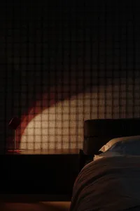 Modern bedroom with textured fabric walls and a lamp casting a warm light.