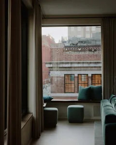 A modern living room with a view of the city, featuring contemporary furniture and a minimalist aesthetic.