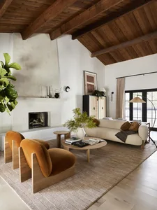 A modern living room featuring wooden furniture, a concrete fireplace, and fabric seating.