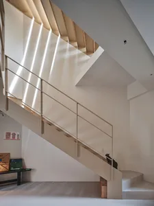 Modern, industrial-style staircase with metallic railing and steps, featuring geometric shapes and a minimalist aesthetic.