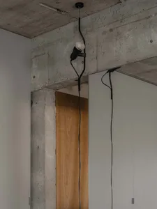 極簡室內空間，裸露混凝土牆面搭配懸吊燈具。