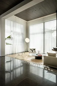 A minimalist living room with transparent curtains and polished concrete flooring.