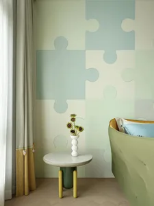 A bedroom featuring a wall covered with fabric panels, a green round table with a vase of sunflowers, and a blue and yellow b