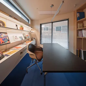 A modern home office featuring a sleek desk, comfortable chair, and organized shelves.