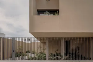A modern house with a concrete exterior featuring a large patio and a metal fence.