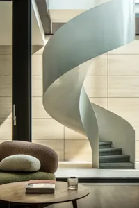 A modern interior design featuring a concrete spiral staircase with minimalist aesthetics.