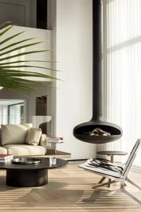 A modern minimalist living room with a hanging fireplace, white walls, and wooden flooring.