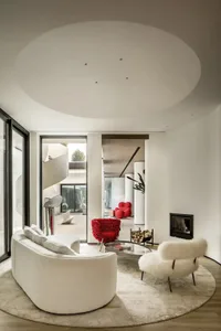 Modern living room with white and red furniture, circular ceiling, and large windows.