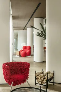 Modern interior design featuring wooden columns and a red knit-fabric covered chair.