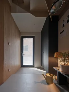 A modern minimalist entryway featuring a concrete floor, minimal decor, and a window with blinds allowing natural light to fi