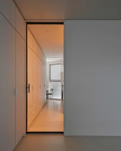 A minimalist interior space featuring sleek, white walls and a well-lit corridor with a view of a simple, uncluttered room wi