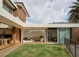 Modern residential backyard featuring wooden exterior and interior, with a comfortable seating area and a green lawn.