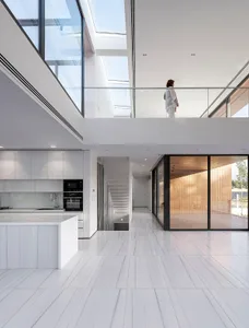 A modern residential kitchen featuring white tiles and glass walls