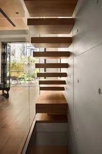 Modern residential interior with a wooden staircase featuring sleek steps and a minimalist design.