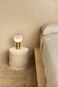 A minimalist bedroom featuring a concrete bedside table and lamp.