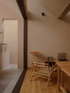A minimalist home office with wooden furniture, including a desk, chair, and small shelf.