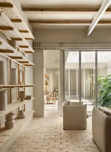 A minimalist living room with concrete walls, wooden furniture, and glass partitions.